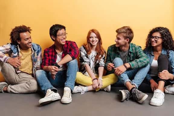 Group of diverse young adults sitting on the floor against a yellow wall